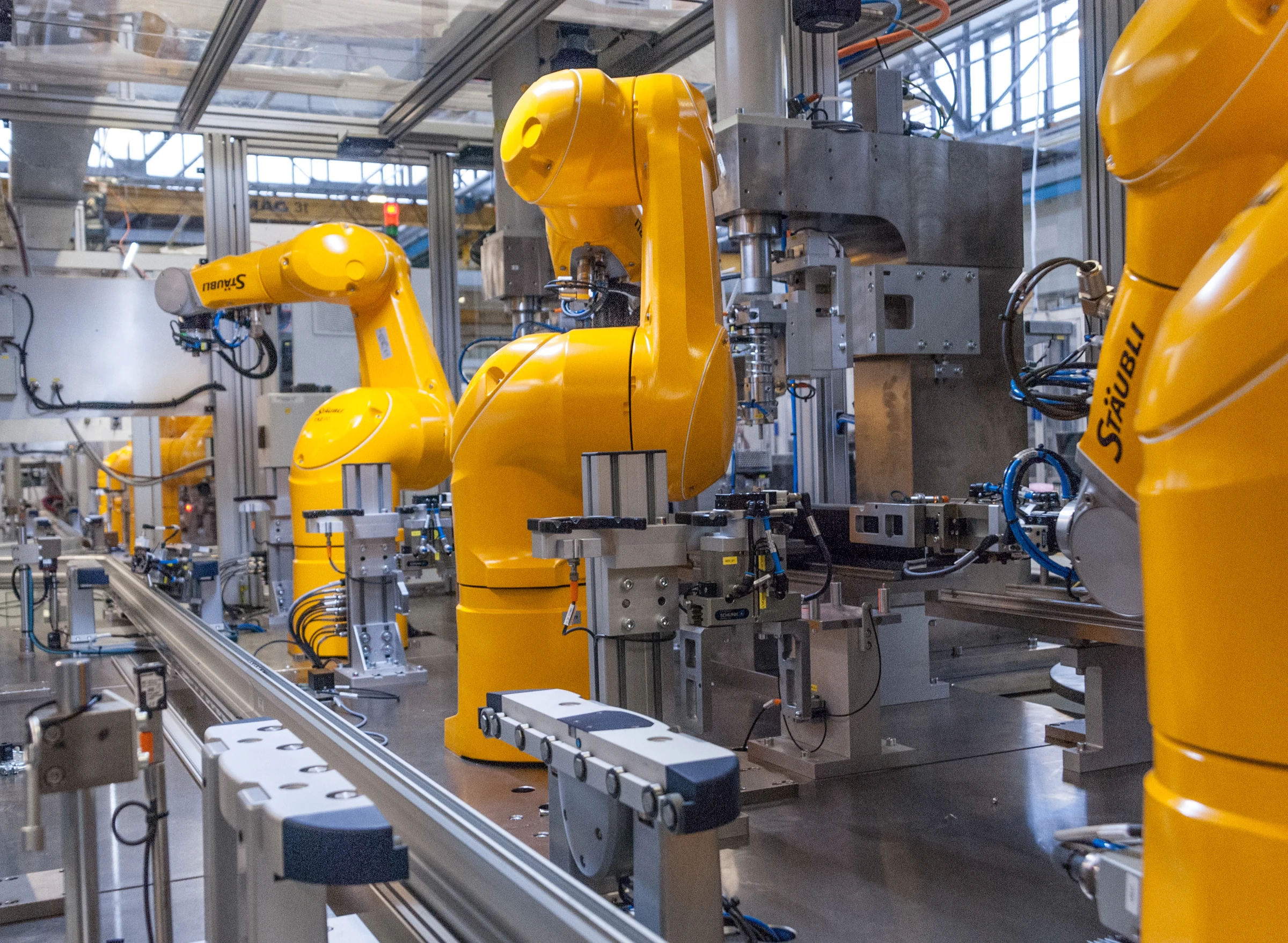 Stäubli industrial robot arms on a manufacturing line.